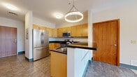 Located at 44 Exchange Blvd in the heart of downtown Rochester, NY, this two-bedroom, two-bathroom unit offers a well-organized and functional single-floor layout. The entryway greets you with warm wood-toned doors and tile flooring that carries throughout the main living areas. The kitchen is a standout feature, equipped with stainless steel appliances including a full-size refrigerator, range, microwave, and dishwasher, complemented by light maple cabinetry, dark granite countertops, a peninsula with seating potential, and stylish pendant lighting overhead. The combined dining and living room provides an open, versatile space bathed in natural light from large windows offering views of the surrounding cityscape. Both bedrooms are carpeted for comfort, with the primary bedroom featuring a double-door closet and ample floor space. The den offers additional flexibility as a home office or secondary living area, with high clerestory windows providing natural light. Two full bathrooms include tile flooring, wood-toned vanities, and bathtub/shower combinations. Additional conveniences include three closets, a pantry, dedicated laundry space, and a private balcony. The unit's warm wood accents and neutral palette create a cohesive, welcoming atmosphere throughout.