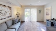 This two-floor home offers a thoughtfully designed layout that balances comfort and functionality across its living spaces. The kitchen is a standout feature, outfitted with rich dark wood cabinetry, granite-style countertops, and a full suite of stainless steel appliances including a refrigerator, electric range, and dishwasher. Track lighting illuminates the workspace, and a convenient in-unit stacked washer and dryer is seamlessly integrated nearby, adding to the home's practicality.

The living area is bright and welcoming, with plush carpeted flooring and a sliding glass door that opens to an outdoor patio, framing a lush green view and filling the room with natural light. The bedrooms are generously sized, each featuring soft carpeting and large windows dressed with sheer curtains and blinds that allow for adjustable natural light. The primary bedroom includes a ceiling fan and ample closet space with built-in shelving. A secondary bedroom comfortably accommodates multiple beds, making it ideal for guests or shared living.

The bathroom is clean and well-appointed, featuring a tub-shower combination with white tile surround, a floral shower curtain, and coordinated blue-toned accents. Warm neutral tones throughout the home create a cohesive and inviting ambiance across both floors.