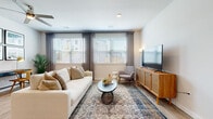 This single-floor residence offers a cohesive, modern aesthetic anchored by light wood-tone flooring and a neutral color palette that flows seamlessly through each room. The living area serves as the heart of the space, featuring dual windows dressed with horizontal blinds and soft drape panels that allow generous natural light while maintaining privacy. A ceiling fan overhead, a large sectional sofa, a round accent coffee table, and a warm wood media console create a comfortable and functional gathering space. A secondary sitting area provides additional flexibility with city views visible through its own set of large windows.

The kitchen is well-equipped with white shaker cabinetry, granite-style countertops, stainless steel appliances including a French door refrigerator, an electric range, and a built-in microwave. A peninsula with seating offers a casual dining option and connects the kitchen to the main living areas. Ample closet and pantry space is accessible nearby.

The bedrooms are bright and restful, each with large windows, ceiling fans, and light wood flooring. The primary bedroom accommodates a king-sized bed comfortably. The bathroom features white cabinetry, a large vanity mirror with overhead lighting, granite countertops, and a tub-shower combination with marble-style tile surround.