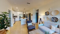 This well-designed single-floor residence offers a bright and cohesive open-concept layout that seamlessly connects the living, dining, and kitchen areas. Light wood-style flooring flows throughout the main living space, complementing the warm, neutral color palette and crown molding details.

The kitchen is a standout feature, outfitted with crisp white shaker cabinets, light quartz countertops, a gray tile backsplash, and a full suite of stainless steel appliances including a French door refrigerator, electric range, and built-in microwave. A central island with a sink provides additional prep space and casual seating. An in-unit washer and dryer are also conveniently located nearby.

The living room is airy and welcoming, featuring a ceiling fan, large windows with plantation-style blinds that invite natural light, and a glass door leading to an outdoor balcony area. The bedrooms are comfortably sized with plush carpeting and ample natural light. The bathroom features a dual-sink vanity with white cabinetry, quartz countertops, and light flooring, with direct access to the adjacent bedroom.

Completing the residence is an attached private garage with a roll-up door, offering secure parking and additional storage space.