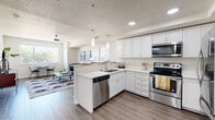 Located at 2255 S 300 E in South Salt Lake, Utah, this single-floor residence offers a thoughtfully designed open-concept layout with modern finishes throughout. The kitchen is a standout feature, equipped with stainless steel appliances including a range, microwave, and dishwasher, complemented by crisp white cabinetry, quartz countertops, and pendant lighting above a peninsula with bar seating. Wood-style flooring flows seamlessly from the kitchen into the dining and living areas, creating a cohesive, airy feel. The living room is generously proportioned, filled with natural light from multiple windows, and opens directly to the kitchen and dining space for effortless entertaining. The unit includes multiple bedrooms, each carpeted for comfort and featuring large windows with views of the surrounding area. The primary bedroom is well-sized with ample room for furnishings. Bathrooms are finished with white cabinetry, quartz countertops, and wood-style flooring; one bathroom includes a tub/shower combination with a clean, bright aesthetic. Neutral tones, recessed lighting, and a textured ceiling are consistent throughout, contributing to a polished and contemporary ambiance well-suited for comfortable everyday living.