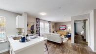 This single-floor unit on SW 34th Street in Gainesville, FL offers a well-designed, open-concept layout with wood-style flooring running throughout. The kitchen is outfitted with white cabinetry, stainless steel appliances, a deep single-basin sink, and a peninsula with bar seating that flows seamlessly into the dining and living areas. Natural light enters through multiple windows dressed with blinds and decorative curtains, contributing to a bright and welcoming atmosphere.

The living area provides generous space for lounging and entertaining, with neutral-toned walls that complement a variety of décor styles. A dedicated sitting nook with large windows offers an ideal spot for relaxing or working. The primary bedroom features a ceiling fan, a bold teal accent wall, and ample space, while additional bedrooms include closets with built-in shelving and natural light from exterior-facing windows. One flexible room is presented as a home office.

The bathroom includes a tub-shower combination, vanity with granite-style countertops, and wood-look tile flooring. Throughout the unit, the consistent use of neutral tones, modern fixtures, and durable flooring creates a cohesive and contemporary living environment.