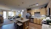 This 2-bedroom, 2-bathroom residence offers a thoughtfully designed single-floor layout that maximizes both comfort and functionality. The open-concept kitchen and living area serve as the heart of the home, creating a spacious and inviting atmosphere ideal for both everyday living and entertaining.

The kitchen is outfitted with warm maple cabinetry, granite countertops, and a full suite of stainless steel appliances, including a refrigerator with ice maker, dishwasher, and a built-in microwave. A decorative mosaic tile backsplash adds a stylish contrast to the cabinetry, while track lighting overhead ensures the workspace is well-illuminated. A central kitchen island with a granite surface and built-in shelving provides additional prep space and casual seating with padded bar stools.

Pendant lighting above the island adds a refined touch, flowing naturally into the open living area beyond. The living space features wood-look flooring that runs throughout, lending warmth and continuity across the floor plan. Large windows dressed with curtains allow ample natural light to fill the space. The overall design balances modern aesthetics with practical features, making this a comfortable and well-equipped two-bedroom home.