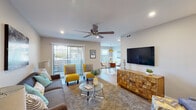 This single-floor residence offers a thoughtfully designed open-concept layout that seamlessly connects the living, dining, and kitchen areas. The living room is bright and welcoming, featuring recessed lighting, a ceiling fan, and a sliding glass door that opens to an outdoor space, allowing natural light to flow throughout. The room comfortably accommodates a generous seating arrangement alongside a large media console, making it ideal for both relaxing and entertaining.

Adjacent to the living area, the dining space features stylish pendant lighting above a glass-top dining table, complemented by warm wood-toned flooring. The kitchen is outfitted with white shaker cabinetry, granite countertops, a white subway tile backsplash, and stainless steel appliances, offering both functionality and a clean, modern aesthetic.

The primary bedroom includes dual closets and direct access to an en-suite bathroom, which features white cabinetry and a granite vanity. A secondary bedroom, carpeted and equipped with its own ceiling fan and a window for natural light, provides versatile space suitable as a guest room or home office. Each bathroom maintains a consistent design language with neutral tones and quality finishes throughout. The cohesive color palette and contemporary touches make this a comfortable and visually appealing living space.
