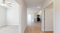 Located at 4039 W Village Pkwy in Ellenwood, GA, this single-floor, 2-bedroom, 2-bathroom residence offers a clean, modern aesthetic with consistent light wood-style flooring and neutral tones throughout. The open-concept kitchen is a standout feature, showcasing granite countertops, a large center island with a single-basin sink, gray shaker-style cabinetry, black appliances, and both track and pendant lighting. The kitchen flows seamlessly into the living area, which benefits from natural light through sliding glass doors that open to an outdoor view, and is outfitted with a ceiling fan. The primary bedroom offers comfortable proportions, a ceiling fan, and access to a spacious walk-in closet with built-in wire shelving. The second bedroom also features a ceiling fan, a standard closet, and a window with outdoor views. Both bathrooms are finished with granite-topped vanities, gray cabinetry, and large-format tile surrounds — one featuring a walk-in shower and the other a full soaking tub. The consistent use of quality materials, modern fixtures, and light, neutral colors creates a cohesive and inviting atmosphere throughout the home.
