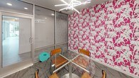 Located at 1270 Spring St NW in Atlanta's dynamic Midtown neighborhood, this single-floor commercial space makes a bold design statement from the moment you enter. The most striking feature is the vivid hot-pink wallpaper adorned with a repeating white animal motif, which covers multiple walls and instantly energizes the interior with a playful yet professional character.

The space is centered around a compact meeting area furnished with a round glass-top table and wood-and-metal chairs, creating an intimate setting ideal for small group collaboration or client meetings. A sculptural starburst chandelier with linear LED elements provides bright, focused overhead lighting that complements the modern aesthetic.

Floor-to-ceiling glass partitions and aluminum-framed glazed walls define the space while maintaining visual openness and transparency, allowing natural light to filter through from adjacent areas. The patterned carpet in muted grey tones grounds the space and balances the vibrancy of the wallpaper, while the neutral white ceiling and grey walls elsewhere provide a clean contrast.

The overall design is contemporary and intentional, blending bold artistic wallcoverings with sleek, minimalist furnishings. The combination of transparency through glass walls, vibrant accent décor, and functional meeting furniture makes this a distinctive and memorable workspace in the heart of Atlanta.