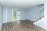 Located at 14979 E 12 Mile Rd in Warren, Michigan, this two-story home offers a well-organized layout across both levels, with distinct material choices that define each area of the space. The main level features rich, dark hardwood-style flooring that runs throughout the living and dining areas, creating a cohesive and polished look. The living room is generously sized, bathed in natural light from a sliding glass door that opens to the outdoors, and includes a staircase with a white railing leading to the upper floor. The adjacent dining area connects seamlessly to the kitchen, which is equipped with white shaker-style cabinetry, light granite countertops, stainless steel appliances including a dishwasher, and matching hardwood-style flooring. A hallway on the main level provides access to additional rooms and closet storage. Upstairs, the bedrooms are finished with wall-to-wall carpet and painted in soft, neutral tones. One bedroom features a large window with views of mature trees, while another offers a spacious built-in shelving unit accessible through a dedicated doorway. The upper level also includes a full bathroom with a tiled tub-shower combination, a white vanity with solid countertops, and hardwood-style flooring, completing the home's clean and functional design.