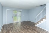 Located at 14979 E 12 Mile Rd in Warren, Michigan, this two-story home offers a well-organized layout across both levels, with distinct material choices that define each area of the space. The main level features rich, dark hardwood-style flooring that runs throughout the living and dining areas, creating a cohesive and polished look. The living room is generously sized, bathed in natural light from a sliding glass door that opens to the outdoors, and includes a staircase with a white railing leading to the upper floor. The adjacent dining area connects seamlessly to the kitchen, which is equipped with white shaker-style cabinetry, light granite countertops, stainless steel appliances including a dishwasher, and matching hardwood-style flooring. A hallway on the main level provides access to additional rooms and closet storage. Upstairs, the bedrooms are finished with wall-to-wall carpet and painted in soft, neutral tones. One bedroom features a large window with views of mature trees, while another offers a spacious built-in shelving unit accessible through a dedicated doorway. The upper level also includes a full bathroom with a tiled tub-shower combination, a white vanity with solid countertops, and hardwood-style flooring, completing the home's clean and functional design.