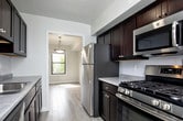 This two-floor residence on Reading Road in Edison, New Jersey offers a well-organized layout designed for comfortable everyday living. The galley-style kitchen is a functional highlight, featuring dark espresso cabinetry, light stone countertops, subway tile backsplash, light wood-style tile flooring, and a full suite of stainless steel appliances including a gas range, built-in microwave, refrigerator, and dishwasher. Adjacent to the kitchen, a dining area provides a natural flow for entertaining.

The carpeted living area is generously proportioned and filled with natural light courtesy of a sliding glass door that opens onto a private balcony, offering outdoor views. A staircase with a white railing connects the two floors, leading to an open upper-level landing bathed in sunlight from multiple windows.

The bedrooms are carpeted and bright, each featuring windows with blinds for adjustable light control. Closet space is well-provided, with at least one bedroom featuring a double-door reach-in closet with a built-in rod system. The bathroom is clean and modern, appointed with white subway tile surrounding a soaking tub and shower combination, along with tile flooring and a dark wood vanity.