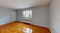 Located at 42 Ethan Dr in New Providence, NJ, this single-floor, one-bedroom, one-bathroom unit offers a well-organized layout with a mix of updated finishes and classic character. Warm-toned hardwood flooring flows throughout the living room and bedroom, complementing soft gray walls and clean white trim to create a bright, cohesive atmosphere. The living room is a comfortable, open space with windows that allow natural light to filter in, offering views of surrounding greenery. A baseboard radiator provides efficient heating throughout the main living areas.

The kitchen stands out as a clear highlight, featuring crisp white shaker-style cabinetry, white quartz countertops, and a full suite of stainless steel appliances including a gas range, over-the-range microwave, and refrigerator. Light tile flooring in the kitchen area contrasts cleanly with the wood floors elsewhere. A louvered door adds a functional design detail at the kitchen entry.

The generously sized bedroom includes a window with outdoor views, a baseboard radiator, and direct access to an adjoining room. The bathroom is finished in an all-white palette with marble-look tile flooring, a full soaking tub with tiled surround, and a white vanity, delivering a clean and polished look throughout.