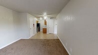 Located at 3210 Junction St in Dallas, TX, this single-story, 2-bedroom, 1-bathroom unit offers a practical and functional layout across a compact yet efficient floor plan. The combined kitchen and living room serves as the heart of the home, with the living area featuring neutral-toned carpet, white walls, a textured ceiling, and a front entry door flanked by a window that allows natural light to filter in. The kitchen is equipped with warm oak cabinetry, a gas range, a refrigerator, a tile countertop, and a tiled backsplash, with light ceramic tile flooring tying the space together. A hallway connects the main living areas to the bedrooms, and is fitted with a ceiling fan for added comfort. Both bedrooms feature plush carpet flooring and neutral walls, offering versatile, move-in-ready spaces. The primary bedroom includes a closet for dedicated storage. The single bathroom is finished with full wall-to-ceiling tile surrounding a bathtub-shower combo, complemented by tile flooring. Throughout the unit, consistent use of neutral tones, white trim, and brass hardware details provide a cohesive and clean aesthetic.