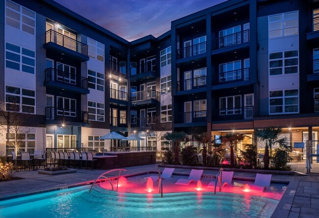 Poolside Scene with Built-In Loungers and Illuminated Water Features - NoDa Flats