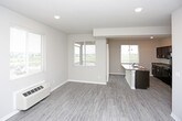 This single-floor residence offers a thoughtfully designed layout with consistent finishes throughout. The kitchen is a standout feature, showcasing rich dark espresso cabinetry with sleek hardware, granite-style countertops, and a full suite of black appliances including an electric range, microwave, and refrigerator. A large kitchen island with a double stainless steel sink and pendant lighting above adds both function and style. An in-unit washer and dryer are conveniently accessible just off the kitchen area.

The living spaces are finished with light wood-look luxury vinyl plank flooring, neutral gray walls, and recessed lighting, creating a bright and airy ambiance. Multiple windows allow natural light to fill the rooms, enhancing the open feel. Individual climate control units are present in the living and bedroom areas for added comfort.

The bedroom features plush carpeting, a ceiling fan with light fixture, a window with exterior views, and its own climate control unit. The bathroom is finished with the same dark cabinetry, granite-style vanity countertop, a large mirror, and light wood-look flooring, maintaining a cohesive design aesthetic. Clean white trim and baseboards throughout tie the entire space together with a polished, move-in-ready appeal.