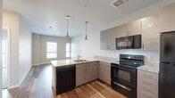 Located at 5730 W 89th Ave in Westminster, CO, this efficiently designed one-bedroom, one-bathroom unit offers a well-appointed single-floor layout. The open-concept kitchen and living area serves as the heart of the space, featuring wood-look flooring, gray flat-front cabinetry with brushed nickel hardware, granite-style countertops, and a full suite of black appliances including an electric range, over-the-range microwave, dishwasher, and refrigerator. Elegant pendant lighting hangs above the kitchen peninsula, which also houses a stainless steel sink. The living area benefits from natural light through large windows, creating a bright and welcoming atmosphere. The bedroom is carpeted for comfort, with a large sliding glass door that invites additional natural light and outdoor views, complemented by a dedicated closet with built-in rod storage. The full bathroom is finished with the same granite-style countertop, dark cabinetry, wood-look flooring, and a tub/shower combination. A stacked in-unit washer and dryer is also included, adding everyday convenience. Neutral wall tones throughout lend a clean, modern aesthetic to the entire space.