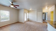 Located at 7701 TX-191 in Odessa, Texas, this single-story unit offers a practical and well-organized layout designed for comfortable everyday living. The open living area serves as the heart of the space, featuring warm neutral-toned carpet, a ceiling fan with light fixture, and multiple windows that allow natural light to filter in. A door provides direct access to the exterior, adding convenience to the living space.

The galley-style kitchen is efficiently arranged with rich, dark-wood cabinetry lining both walls, offering generous storage. Granite-style countertops and a stainless steel sink complement the dark appliances, including an electric range with microwave above. Wood-look flooring runs throughout the kitchen, adding warmth and easy maintenance. A doorway leads to a dedicated laundry area just off the kitchen.

The bedrooms are carpeted and feature ceiling fans with light fixtures and windows with blinds that provide natural light and privacy. Each room offers a clean, neutral palette suitable for various furnishing styles.

The bathroom includes a full tub and shower combo with white tile surround, wood-look flooring, dark wood cabinetry for storage, and granite-style countertops, maintaining a consistent design aesthetic throughout the unit.