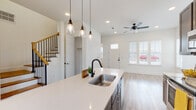 This contemporary two-story home offers a well-designed open-concept layout that seamlessly connects the kitchen, dining, and living areas on the main floor. The kitchen is a standout feature, equipped with dark taupe cabinetry, stainless steel appliances, a white quartz countertop island with a double basin sink and matte black faucet, and pendant lighting overhead. A subway tile backsplash and a sliding glass door leading to a private outdoor area add both style and functionality. The living area is bright and welcoming, with light luxury vinyl plank flooring, recessed lighting, a ceiling fan, and multiple windows that invite an abundance of natural light. A coat closet and a powder room with a pedestal sink and oval mirror are conveniently located on the main level. The staircase, accented with wood handrails and black metal balusters, leads to the upper floor, where carpeted bedrooms offer a comfortable retreat, each with ceiling fans and windows overlooking the surrounding neighborhood. A full bathroom upstairs features a tub-shower combination with white tile surround, wood-toned cabinetry, and modern matte black fixtures. Throughout the home, crisp white walls and consistent flooring create a clean, cohesive aesthetic.