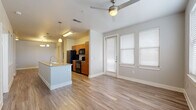 Located at 7803 South New Braunfels Avenue in San Antonio, TX, this single-story, 2-bedroom, 2-bathroom home offers a well-designed open-concept layout with modern finishes throughout. The living and dining area features warm wood-look flooring, a ceiling fan, and large windows with blinds that allow ample natural light, with a patio door providing outdoor access.

The galley-style kitchen is equipped with warm wood cabinetry, granite countertops, black appliances including a range, microwave, refrigerator, and dishwasher, as well as a double basin sink and pendant lighting overhead. A kitchen island with additional counter space and storage connects seamlessly to the living area.

Both bedrooms are carpeted, with ceiling fans and multiple windows that bring in natural light. The spacious primary bedroom includes its own closet, and the home features a total of three closets for generous storage. Both bathrooms are finished with wood cabinetry, granite countertops, subway tile tub-and-shower surrounds, and wood-look flooring.

Additional spaces include a dedicated utility room and a patio. The home's neutral color palette, consistent finishes, and functional floor plan make it a practical and comfortable residence in San Antonio.
