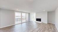 Located along Harbor Blvd in Oxnard, CA, this 2-bedroom, 2-bathroom waterfront residence offers stunning marina and harbor views throughout. The main living area is bright and open, featuring light wood-look flooring, recessed lighting, and a sleek fireplace framed by large sliding glass doors that lead to a private balcony overlooking sailboats, lush greenery, and the shimmering water beyond. Natural light pours in through expansive windows and corner glass panels, creating an airy, coastal ambiance.

The kitchen is outfitted with white shaker cabinetry, white quartz countertops, and stainless steel appliances, providing a clean and functional workspace. Both bedrooms are generously sized with large closets, light-toned flooring, and windows offering views of the harbor or surrounding grounds. The spacious primary bedroom connects to a well-appointed bathroom featuring a frameless sliding glass shower enclosure with matte black hardware and modern fixtures.

The second bathroom echoes the same contemporary aesthetic. Throughout the residence, a neutral color palette, updated finishes, and consistent flooring tie each room together cohesively. A landscaped lawn with mature trees is visible from the balcony, completing this polished coastal retreat.