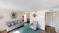 This single-floor unit at Albrook Drive in Denver, Colorado offers a well-organized layout designed for comfortable everyday living. The living room serves as the central gathering space, featuring wood-style flooring, a textured ceiling, and multiple windows fitted with vertical blinds that allow generous natural light to fill the room. The open sightlines connect the living area to the dining space, creating a cohesive flow throughout the common areas.

The kitchen is equipped with dark wood cabinetry, a double-basin sink, and a electric range, complemented by wood-style flooring that carries through from the main living area. A ceiling fan with a light fixture overhead illuminates the adjacent dining area, which comfortably accommodates a table and chairs.

Two bedrooms provide private retreats, each with carpeted floors, textured ceilings, and windows that bring in natural light. One bedroom includes a closet with an open shelving system, while the other features built-in closet storage. The bathroom includes a full tub and shower combination with white tile surround and a curtain rod, paired with a closet for added storage. Overall, the unit presents a cohesive, neutral palette throughout.