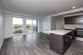 Located at 600 E Court Ave in the heart of Des Moines, Iowa, this thoughtfully designed one-bedroom, one-bathroom unit offers a bright and modern living experience. The open-concept layout seamlessly connects the kitchen and living area, creating a spacious, airy feel throughout. Light-toned hardwood flooring runs throughout the unit, complementing the clean white walls and contemporary finishes.

The kitchen is a standout feature, boasting rich dark-wood cabinetry, a white quartz countertop island, stainless steel appliances — including a full-size refrigerator, range, microwave, and dishwasher — and a sleek tile backsplash. Recessed lighting adds warmth and functionality to the space.

The living area is bathed in natural light through floor-to-ceiling sliding glass doors that open onto a private balcony, offering panoramic views of the Des Moines cityscape and surrounding greenery. A ceiling fan adds comfort to this inviting space.

The bedroom is well-proportioned and bright, with large windows framing additional city views. It is served by a generously sized walk-in closet with wire shelving for ample storage. The bathroom features a dark-wood vanity with a white countertop, a framed mirror, and warm hardwood-style flooring. The unit combines urban convenience with refined, modern design.