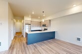 Located at 5127 Labounty Rd in Ferndale, WA, this thoughtfully designed 2-bedroom, 2-bathroom residence offers a clean, modern aesthetic across a single floor. The open-concept living and kitchen area serves as the heart of the home, featuring light wood-look flooring, recessed lighting, and a striking peninsula with a bold navy base and white countertop — ideal for casual dining or entertaining. The kitchen is well-appointed with two-tone cabinetry in gray tones, stainless steel appliances including a refrigerator, range, and microwave, and ample upper and lower cabinet storage. A bank of triple windows in the living area floods the space with natural light and provides views of the surrounding landscape. A central hallway connects the bedrooms and bathrooms, maintaining a clear and functional layout. Both bedrooms feature plush carpet flooring and sliding closet doors, offering comfortable, private retreats. The bathrooms are finished in a clean, minimal style with light flooring and dark cabinetry. A dedicated laundry room houses a full-size Whirlpool washer and dryer with overhead shelving, adding everyday convenience. The overall design is bright, neutral, and move-in ready.