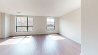 Located at 1 Uptown Cir in Normal, IL, this well-appointed 2-bedroom, 2-bathroom residence offers a thoughtfully designed single-level floor plan with a clean, contemporary aesthetic. The open-concept kitchen and living area serves as the heart of the home, featuring rich dark wood cabinetry, light stone countertops, stainless steel appliances including a gas range and French door refrigerator, and elegant pendant lighting over the kitchen island. Warm hardwood flooring flows throughout the main living areas, complementing the bright, neutral color palette. The spacious living room is bathed in natural light through large floor-to-ceiling windows that frame views of the surrounding Uptown neighborhood. Both bedrooms are generously sized, with soft carpet flooring, built-in closet storage, and large windows that continue the home's emphasis on natural light. The primary bathroom features a floating double vanity with stone countertops, a large mirror, and a walk-in glass shower, while the secondary bathroom includes a full soaking tub with tile surround. A hallway connects all rooms efficiently, and dedicated closet space adds practical storage. The overall ambiance is modern, clean, and inviting.