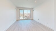 Located at 20 Medford St in Somerville, MA, this thoughtfully designed unit offers a clean, contemporary aesthetic throughout its single floor. Light-toned hardwood flooring flows seamlessly across the space, complementing the bright white walls and recessed lighting that keep the interior feeling open and airy.

The combined kitchen and living area serves as the heart of the unit. The kitchen is outfitted with white flat-front cabinetry, white quartz countertops, a matte black sink fixture, and a full suite of stainless steel appliances, including a refrigerator, dishwasher, range, and over-the-range microwave. A wall-mounted mini-split unit provides efficient climate control for the living area. Large floor-to-ceiling windows flood the living space with natural light and frame views of the surrounding Somerville neighborhood.

A long hallway lined with four closets provides exceptional storage capacity, a rare and practical feature. The in-unit laundry adds everyday convenience. The bathroom is finished with neutral large-format floor tile, a floating wood-toned vanity with a white countertop, a full-width mirror, and matte black hardware and fixtures, delivering a polished, modern look. Recessed lighting and clean white walls complete the refined, minimalist character of this well-appointed Somerville residence.