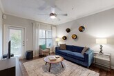 This thoughtfully designed single-floor residence offers a comfortable and cohesive living experience across its one-bedroom, one-bathroom layout. The open-concept living and kitchen area forms the heart of the home, anchored by striking decorative columns with an elegant archway that frames the transition between spaces. Rich hardwood-style flooring runs throughout the main living areas, complemented by crown molding and neutral gray tones that lend a polished, contemporary feel.

The kitchen is equipped with stainless steel appliances, including a range, over-the-range microwave, dishwasher, and refrigerator, all set against granite-style countertops and sage-toned cabinetry. A peninsula with bar seating serves as a convenient casual dining option and connects seamlessly to the living room. The living area is bright and airy, with large windows allowing generous natural light and a ceiling fan overhead.

The bedroom offers a tranquil retreat with plush carpet flooring, windows with garden views, and a dedicated closet. The full bathroom features a granite-topped vanity, tile flooring, and a tub-shower combination with classic tile surround. A hallway connects the private spaces efficiently, completing this well-organized and comfortable residence.