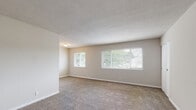 Located on Butternut Drive in Hampton, Virginia, this single-floor residence offers a straightforward and functional layout well-suited for comfortable everyday living. The spacious living area is finished with wall-to-wall carpeting and neutral-toned walls, creating a clean and versatile backdrop. Multiple windows allow ample natural light to flow through, offering views of the surrounding greenery outside. The textured ceilings and clean white trim throughout contribute to a consistent, understated aesthetic. The bedrooms are generously sized, each carpeted and bathed in natural light from their respective windows. At least one bedroom features a full-width bifold closet, providing practical built-in storage. The kitchen is equipped with wood-toned cabinetry and includes a gas range, offering a functional cooking space with essential appliances in place. The bathroom presents a classic design with white subway tile surrounding a full bathtub and shower, dark accent tile trim, a white vanity, and light tile flooring — a timeless and easy-to-maintain space. The floor plan, visible in the dollhouse view, reveals a well-organized layout with distinct living, sleeping, kitchen, and bathroom zones all on one level, making navigation intuitive and efficient throughout the home.