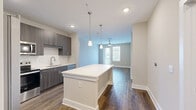 This well-appointed 3-bedroom, 2-bathroom single-story home in Panama City, Florida offers a thoughtfully designed layout with modern finishes throughout. The open-concept living area seamlessly connects the kitchen, dining, and living spaces, creating a bright and functional gathering space. The kitchen is a standout feature, boasting dark wood-grain cabinetry, a white quartz countertop island with pendant lighting, a full suite of stainless steel appliances, and a classic subway tile backsplash. Rich hardwood-style flooring runs throughout the entire home, adding warmth and cohesion. The living area is anchored by a ceiling fan and opens directly to a private patio through a glass door, inviting natural light and outdoor access. Each of the three bedrooms is generously proportioned with neutral tones, ceiling fans, and hardwood-style flooring. The primary bedroom offers a spacious walk-in closet with wire shelving. Both bathrooms feature wood-grain vanities with white countertops and wood-look tile flooring. A dedicated laundry room houses a full-size Whirlpool washer and dryer. With five closets providing ample storage and a well-connected floor plan, this home combines everyday practicality with contemporary style.