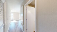 Located at 215 W 14th St in Los Angeles' South Park neighborhood, this studio unit offers a well-planned layout that maximizes every square foot across a single floor. The open-concept kitchen and living area serves as the heart of the space, featuring warm wood-look flooring that flows throughout. The modern kitchen is outfitted with white cabinetry, stainless steel appliances including a refrigerator, range, dishwasher, and built-in microwave, complemented by a tiled backsplash and ample counter space. Large windows in the living area flood the space with natural light and frame impressive views of the Los Angeles skyline and surrounding cityscape, adding a sense of openness and depth. A well-appointed hallway connects the main living space to the supporting rooms, including a closet with louvered doors and a dedicated laundry area with a stacked washer and dryer. The full bathroom is clean and contemporary, featuring wood-look flooring, a white vanity with built-in shelving, and a tiled soaking tub and shower combination. Neutral toned walls, recessed lighting, and consistent flooring throughout create a cohesive, modern aesthetic. A utility room rounds out the functional offerings of this efficiently designed urban residence.