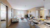 This single-floor residence offers a thoughtfully designed open-concept layout that seamlessly connects the living, dining, and kitchen areas. The living room is a welcoming space finished with plush carpet flooring, warm neutral-toned accent walls, and a sliding glass door that opens to a private balcony overlooking urban surroundings, filling the room with natural light.

The galley-style kitchen is outfitted with stainless steel appliances, including a refrigerator, range, and microwave, complemented by dark wood cabinetry, light countertops, and light wood-tone flooring that adds warmth to the space.

Two well-proportioned bedrooms each feature large windows that draw in abundant natural light and offer views of the surrounding cityscape. Both rooms are finished with soft carpet flooring and neutral walls that create a calm, restful atmosphere.

The unit includes two bathrooms. The primary bathroom features a sliding glass-door walk-in shower with built-in shelving, light wood-tone flooring, and a dark vanity with a clean white countertop. The second bathroom mirrors the modern aesthetic with a tub-shower combination, matching vanity finishes, and light flooring throughout.