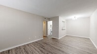 Located at 874 Yorkchester Dr in Houston, TX, this single-floor 1-bedroom, 1-bathroom unit offers a clean, modern aesthetic throughout. The living room greets you with wide-plank wood-look flooring in a warm gray tone, neutral painted walls, and a front-facing window that invites natural light. A pass-through opening connects the living area to the kitchen, which features white cabinetry, light countertops, and white appliances including a refrigerator, range, and dishwasher. The layout flows naturally through a hallway leading to the remaining rooms. The bedroom is a comfortable, well-proportioned retreat finished with plush neutral carpet, a ceiling fan with light fixture, and a window with blinds. It includes access to a spacious walk-in closet outfitted with dual clothing rods on multiple walls, providing generous storage. The bathroom is neatly appointed with wood-look flooring, a single-sink vanity with upper cabinetry, a tiled tub-shower combination, and a light fixture overhead. A dedicated laundry area adds everyday convenience. The unit's consistent neutral palette and updated finishes create a cohesive, move-in-ready atmosphere throughout.