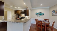 This thoughtfully designed single-story residence offers a comfortable and functional layout across one floor. The open-concept living, dining, and kitchen area forms the heart of the home, where rich hardwood-style flooring and crown molding add a polished aesthetic throughout. The kitchen is outfitted with dark espresso cabinetry, granite countertops, a tile backsplash, and a full suite of stainless steel appliances, including a refrigerator, electric range, and dishwasher. A peninsula counter provides additional workspace and flows naturally into the dining area, which features classic wainscoting detail along the walls. The living room is bright and welcoming, with large windows and a sliding glass door that invite abundant natural light. The bedroom is a comfortable retreat featuring hardwood-style flooring, a ceiling fan, and a window with exterior views. The bathroom is well-finished with granite countertops, a dark-framed vanity mirror, and a shower-tub combination. A dedicated laundry area with a full-size washer and dryer, as well as a closet and hallway, round out the practical amenities of this efficiently organized residence.