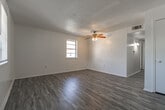 Located at 1011 S James St in Jacksonville, Arkansas, this single-story home offers a practical and well-organized layout with three bedrooms, one full bathroom, a kitchen, and a connecting hallway. The living areas feature light gray wood-look laminate flooring that lends a clean, modern feel, while a textured ceiling adds character throughout. Ceiling fans are present in the main living spaces and bedrooms, promoting airflow and comfort. The spacious primary bedroom is the largest of the three, featuring the same laminate flooring and a ceiling fan with a lighted fixture. The two additional bedrooms are carpeted in neutral tones and each include ceiling fans, natural window light, and closet storage. The kitchen is designed in a galley style, equipped with gray cabinetry, laminate countertops, a double-basin sink, and white appliances including a range and refrigerator, all set over matching wood-look flooring. The full bathroom features updated gray vanity cabinetry, a single-sink vanity with a lighted mirror, wood-look tile flooring, and a tub-shower combination. Natural light flows into rooms throughout the home via blinded windows. The overall aesthetic is clean, neutral, and move-in ready.