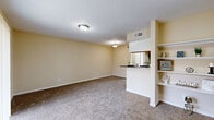 Located on Spencer Hwy in Pasadena, TX, this 1-bedroom, 1-bathroom residence offers a thoughtfully organized single-floor layout designed for comfortable everyday living. The combined kitchen and living room area forms the heart of the home, featuring soft carpeted flooring in the living space and warm beige walls that create a bright, welcoming ambiance. A partial wall with built-in open shelving neatly divides the living area from the kitchen pass-through, adding both style and practicality. The galley-style kitchen is equipped with light wood cabinetry, dark granite-style countertops, tile flooring, and black appliances including a refrigerator, range, and dishwasher, providing ample storage and workspace. The bedroom is generously sized, featuring plush carpeting, a ceiling fan, and a sliding glass door with vertical blinds that opens to an outdoor view, filling the room with natural light. A dedicated closet offers convenient built-in storage. The bathroom features tile flooring, a wide vanity with wood cabinetry and a granite-style countertop, a large mirror, and overhead lighting. Throughout the residence, neutral tones, consistent finishes, and practical design choices combine to create a cohesive and comfortable living environment.