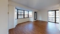 Situated in the heart of Chicago's prestigious Gold Coast neighborhood at 1133 N Dearborn St, this single-floor residence offers a well-designed layout with a variety of thoughtful finishes throughout. The spacious living area is a standout feature, boasting rich hardwood flooring and an expansive curved bay window arrangement that floods the space with natural light and frames sweeping views of the surrounding cityscape. A large sliding glass door leads to a private balcony, further extending the connection to the vibrant urban environment outside. A full-length mirror accent adds a stylish architectural touch to the living space. The galley-style kitchen is efficiently designed with ample white cabinetry, dark countertops, a stainless steel sink, and a full suite of appliances including a stovetop range and refrigerator, with a view toward the balcony providing an airy feel. The bedrooms are carpeted for comfort, each benefiting from windows that bring in natural light and views of neighboring Chicago architecture. The bathroom is clean and functional, featuring tile flooring, a dark-toned vanity with a light countertop, and stainless steel grab bars. Overall, the residence offers a bright, urban living experience in one of Chicago's most sought-after locations.