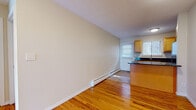 Located at 271 Main St in Farmington, CT, this single-floor unit offers a well-designed layout that maximizes both functionality and comfort. Warm hardwood flooring flows seamlessly throughout the living areas and bedrooms, lending a cohesive and inviting character to the space.

The open living area is generously proportioned, featuring a large sliding glass door fitted with vertical blinds that floods the room with natural light and provides access to an exterior view. A secondary window and a wall-mounted air conditioning unit complement the space, which also benefits from baseboard heating throughout.

The galley-style kitchen is thoughtfully appointed with rich dark granite countertops, warm honey-toned cabinetry, a stainless steel refrigerator, and a full suite of appliances including a range and microwave. A window above the sink allows for natural light to brighten the workspace. A peninsula counter opens the kitchen toward the dining and living area, encouraging an open-concept feel.

The bedrooms are well-sized and bright, each featuring hardwood floors, large windows with blinds, and baseboard heating. The bathroom includes a tub/shower combination, mosaic tile flooring, and a window for ventilation. The unit is accessed through a private entrance, adding a sense of arrival and separation from common areas.