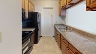 Located at 10398 Valley Forge Dr in Parma Heights, Ohio, this single-floor unit offers a clean, well-maintained interior with a cohesive design throughout. Light wood-style flooring runs through the main living areas and bedrooms, creating a bright and consistent aesthetic that pairs naturally with the crisp white walls found throughout the space.

The living room is an open, welcoming area featuring a large front-facing window fitted with vertical blinds that allow generous natural light, along with a wall-mounted air conditioning unit for climate control. A front entry door with a decorative half-moon transom window adds a subtle architectural detail to the entryway.

Adjacent to the living area, a dining space features vaulted ceiling lines and a pendant light fixture, transitioning into a tiled area that leads to the galley-style kitchen. The kitchen is efficiently laid out with warm wood cabinetry, granite-look countertops, a double sink, and black appliances including a refrigerator, range, and dishwasher, all set on light tile flooring.

The bedrooms are comfortably sized, each featuring the same light wood-style flooring, white walls, and ceiling fans with light fixtures. One bedroom includes a window with natural views.

The bathroom is well-appointed with a dark wood vanity, white countertop, a framed mirror, dark tile flooring, and a glass-enclosed shower stall.