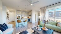 Located at 613 Meadowbrook Pkwy in Colorado Springs, CO, this well-appointed single-floor home offers a thoughtfully designed open-concept layout with contemporary finishes throughout. The heart of the home is a sleek kitchen featuring light gray cabinetry, a large center island with a built-in sink and dishwasher, stainless steel appliances, subway tile backsplash, and dramatic pendant lighting. The kitchen flows seamlessly into a bright living area, where large corner windows flood the space with natural light and offer views of the surrounding neighborhood. Wide-plank wood-style flooring and a ceiling fan add comfort and cohesion to the main living space. The bedrooms are carpeted and generously sized, with clean white walls and ample natural light. A walk-in closet with built-in shelving and hanging rods provides excellent storage. A full bathroom includes a tiled tub-shower combination and wood-style flooring. A standout feature is the built-in home office nook, complete with overhead cabinetry and a quartz desktop surface — ideal for working from home. The overall ambiance is modern and airy, combining functional design with stylish, curated details throughout every room.
