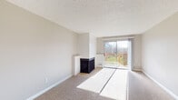 Located at 14095 SW Walker Rd in Beaverton, Oregon, this single-floor residence offers a thoughtfully laid-out living space with a neutral color palette and practical finishes throughout. The living room serves as the centerpiece of the home, featuring plush carpeting, a textured ceiling, and a freestanding fireplace with a tiled surround. A sliding glass door floods the room with natural light and opens directly onto a wood-railed balcony overlooking a green outdoor setting. A ceiling fan provides additional comfort in the adjoining area, which connects seamlessly to the kitchen. The kitchen is well-equipped with white cabinetry, dark countertops, a double-basin sink, a white range, and a dishwasher. Light tile flooring and a window with blinds complete the space, keeping it bright and functional. A hallway connects the main living areas to the private spaces, including a full bathroom appointed with tile flooring, a vanity with dark countertop, and a full tub and shower combination with a curved rod and grab bar. Carpeted throughout the bedrooms and main living areas, the residence offers a comfortable and cohesive feel. The layout is efficient and well-organized, making excellent use of available space across its single floor.