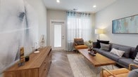 This single-floor unit in Plainfield, Indiana, presents a cohesive modern design highlighted by warm wood-look flooring, soft gray walls, and recessed lighting throughout. The open-concept kitchen serves as a functional centerpiece, equipped with stainless steel appliances, two-tone cabinetry featuring white upper cabinets and dark lower cabinets, and a spacious granite-topped island with an undermount sink. The layout flows directly into the living area, which benefits from large windows dressed with sheer white curtains that invite generous natural light. A private entrance door with a sidelight panel adds a practical and welcoming touch to the living space.

The bedroom is a well-proportioned retreat featuring a ceiling fan, a large window with blinds, and access to a generously sized walk-in closet equipped with wire shelving systems for organized storage. The bathroom is finished with granite countertops, gray cabinetry with brushed nickel hardware, wood-look tile flooring, and a frosted window for privacy. Throughout the unit, clean white trim and neutral tones create a consistent, polished aesthetic that balances modern style with everyday comfort.