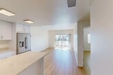 Located at 6830 Cortona Dr in Goleta, California, this modern 1-bedroom, 1-bathroom unit offers a thoughtfully designed open-concept layout finished with light wood-look flooring and crisp white walls throughout. The living room is bright and welcoming, anchored by a sliding glass door that opens to a private balcony overlooking the surrounding neighborhood, filling the space with abundant natural light. Recessed lighting complements the airy atmosphere throughout the main living area.

The kitchen is a standout feature, showcasing white shaker-style cabinetry extending to the ceiling, light stone quartz countertops, and a central island that provides additional prep and seating space. Stainless steel appliances include a gas range, built-in microwave, dishwasher, and a French door refrigerator with an ice and water dispenser.

The bedroom is a comfortable, well-proportioned retreat with a window fitted with blinds for natural light and privacy, complemented by a dedicated closet. The full bathroom features wood-look flooring, a vanity with dark countertop, and a combined tub and shower enclosed with a glass sliding door. Clean lines and a neutral palette create a cohesive, modern aesthetic throughout this efficiently laid-out Goleta residence.