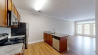 Located at 404 W Smith St in Greensboro, NC, this one-bedroom, one-bathroom unit offers a well-designed single-floor layout that makes efficient use of its space. The open-concept kitchen and living area forms the heart of the unit, featuring warm hardwood-style flooring and elegant crown molding that adds a polished architectural touch throughout. The kitchen is well-appointed with rich wood cabinetry, granite countertops, a subway tile backsplash, and a full suite of stainless steel appliances including a refrigerator, range, microwave, and dishwasher. A peninsula with a built-in sink and additional counter space provides a natural division between the kitchen and the open living area, which benefits from natural light streaming through a glass-paned entry door. The bedroom is a comfortable retreat, finished with plush carpeting, a ceiling fan, and a window with blinds that offers outdoor views. A dedicated closet adds practical storage. The bathroom is cleanly finished with tile flooring, a granite-topped wood vanity, and a full tub-shower combination with brushed nickel fixtures. Neutral wall tones throughout the unit create a calm, cohesive ambiance well-suited to everyday living.