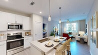 Located in Matthews, NC, this thoughtfully designed 2-bedroom, 2-bathroom residence offers a comfortable and modern living experience across a single floor. The open-concept kitchen and living area serves as the heart of the home, with light wood-tone flooring flowing throughout. The kitchen is equipped with stainless steel appliances, crisp white cabinetry, a large center island with pendant lighting, and a built-in dining nook — ideal for both everyday meals and entertaining. The living room features large windows that invite abundant natural light, a ceiling fan, and a glass door leading to a private outdoor area. The primary bedroom offers a bold accent wall, ceiling fan, and direct access to an en-suite bathroom with a dual-sink vanity, stone countertops, and white cabinetry. The second bedroom is bright and airy, with large windows framing outdoor views. Both bathrooms are finished with clean, neutral tile work and soaking tub-shower combinations. Three closets, including a walk-in with wire shelving, provide generous storage. The overall ambiance is bright, clean, and contemporary, with a neutral color palette that complements the natural light throughout.