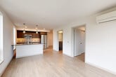 Located in Seattle's Ravenna neighborhood, this thoughtfully designed 2-bedroom, 2-bathroom residence offers a clean, modern aesthetic throughout. Light-toned hardwood-style flooring flows continuously across the entire single-floor layout, creating a cohesive and airy feel.

The open-concept living, dining, and kitchen area forms the heart of the unit. The kitchen is outfitted with dark wood cabinetry, stainless steel appliances including a refrigerator, microwave, and dishwasher, a sleek quartz countertop, and a stainless undermount sink. Stylish pendant lights hang above the kitchen island, and a window above the counter draws in natural light with outdoor views.

Both bedrooms feature large windows that invite abundant natural light and neighborhood views. The primary bedroom includes a wall-mounted HVAC unit and a sliding-door closet, while the second bedroom also benefits from generous window coverage and its own closet access. Four closets are distributed throughout the unit, providing ample storage.

The two bathrooms are finished with wood-toned vanity cabinetry and quartz countertops. One bathroom includes a full soaking tub with tile surround. A stacked in-unit washer and dryer is conveniently located in the hallway area. The overall design is clean, minimal, and well-appointed throughout.