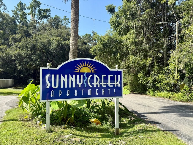 Inviting entrance sign of Sunny Creek Apartments surrounded by lush greenery, promising a tranquil living experience. - Sunny Creek Apartments