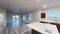 Located at 140 40th Street Dr SE in Cedar Rapids, Iowa, this single-floor unit offers a thoughtfully designed layout with modern finishes throughout. The open-concept kitchen is a standout feature, equipped with rich dark-wood cabinetry, gleaming white countertops, a central island, and a full suite of stainless steel appliances including a refrigerator, range, microwave, and dishwasher. Light-toned wood-style flooring runs through the kitchen and flows seamlessly into the expansive living area, which is bathed in natural light from multiple windows fitted with blinds. Glass doors lead to a private balcony, extending the living space outdoors with views of the surrounding neighborhood. The bedrooms are carpeted for comfort and feature large windows that bring in generous amounts of natural light, along with individual climate control units. The primary bedroom connects to a well-sized walk-in closet with wire shelving, offering ample storage. The bathroom features matching dark-wood cabinetry with brushed nickel hardware and white countertops. A dedicated laundry area houses a full-sized washer and dryer with overhead wire shelving. The unit's neutral color palette and clean architectural lines create a bright, welcoming ambiance throughout.