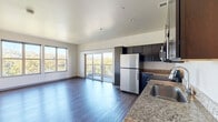Located at 2645 Railroad St in Pittsburgh's Strip District, this two-bedroom, three-bathroom residence offers a thoughtfully designed single-floor layout with modern finishes and impressive natural light. The open-concept kitchen and living area serves as the heart of the home, featuring rich hardwood-style flooring, dark espresso cabinetry, granite countertops, and a full suite of stainless steel appliances. Large windows and sliding glass doors flood the living space with sunlight and lead directly to a private balcony overlooking lush treetops and the river beyond. The spacious primary bedroom captures sweeping waterfront views through a generous bank of windows, while the second bedroom offers its own window with neighborhood views. Both rooms are complemented by hardwood-style flooring and clean, neutral walls. Five closets throughout the unit provide ample storage, including a walk-in closet with built-in wire shelving. The three bathrooms are finished with dark vanity cabinetry, granite countertops, and tub-shower combinations. A dedicated laundry area and a convenient hallway complete the well-organized layout, making this a highly functional and comfortable urban residence.