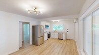 Located at 3005 Leonard St #3 in Raleigh, NC, this well-appointed 2-bedroom, 1-bathroom unit offers a thoughtfully designed single-floor layout with a clean, modern aesthetic. Light hardwood flooring flows seamlessly throughout, complementing the crisp white walls and contemporary finishes found in every room.

The kitchen is a standout feature, showcasing white shaker-style cabinetry with gold hardware, quartz countertops, stainless steel appliances including a refrigerator, range, built-in microwave, and dishwasher, a gold-finish faucet, and a striking sputnik-style chandelier. A window provides natural light and connects the space to the outdoors.

Both bedrooms are well-proportioned and bright, with the primary bedroom offering a generous footprint, a wall-mounted mini-split HVAC unit, and a window with views of surrounding trees. The second bedroom also benefits from natural light and provides easy hallway access. Each room is fitted with stylish drum flush-mount ceiling fixtures with gold accents.

The bathroom features marble-look tile surround in the tub/shower combo, a white vanity, recessed lighting, and light hardwood-style flooring, creating a fresh and elegant atmosphere.

Two hallways connect the space efficiently, and the overall design balances practicality with modern style in a compact, comfortable layout.